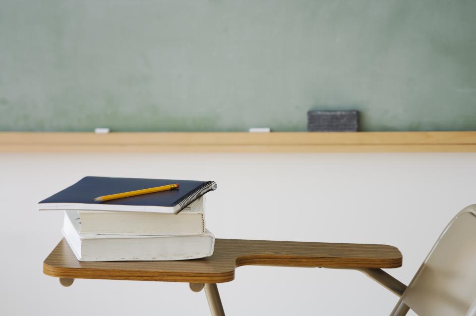 Books, a notebook, and a pencil on a student desk