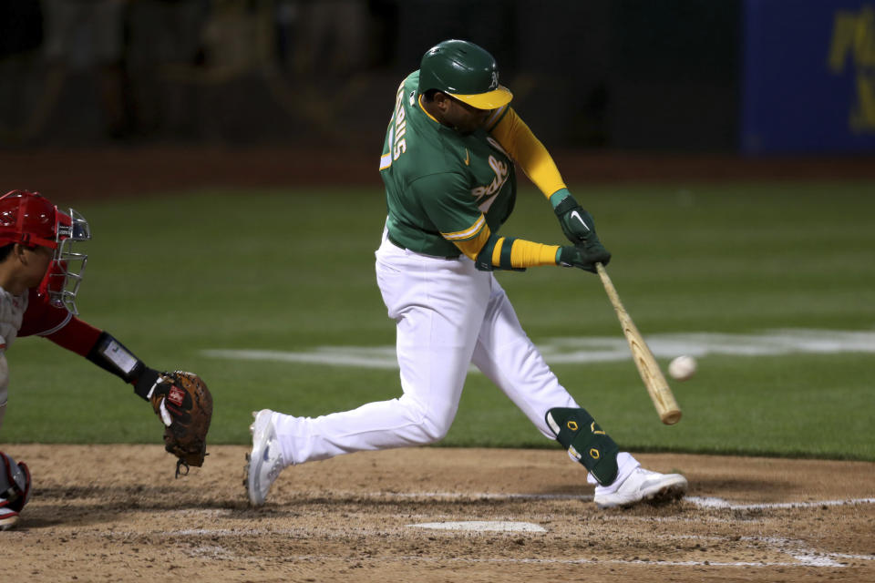 Oakland Athletics' Elvis Andrus hits a two-run double next to Los Angeles Angels catcher Kurt Suzuk during the sixth inning of a baseball game in Oakland, Calif., Tuesday, June 15, 2021. (AP Photo/Jed Jacobsohn)