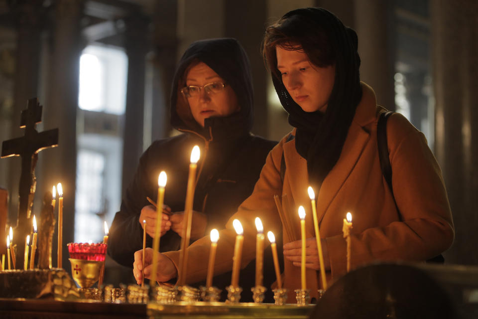 Dos mujeres encienden velas en memoria de las víctimas de una balacera en una escuela de formación profesional en Kerch, Crimea, en una iglesia de San Petersburgo, Rusia, el 18 de octubre de 2018. (AP Foto/Dmitri Lovetsky)