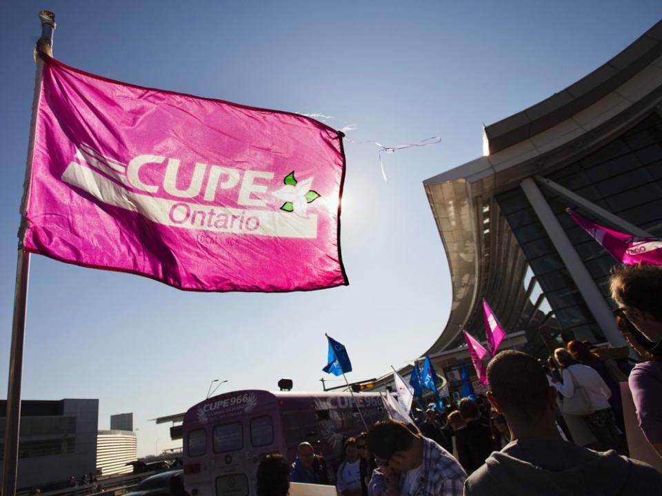 A person holds a flag with the logo of the CUPE, which represents flight attendants from Air Canada, during a protest about labour disputes at the Toronto Pearson International Airport