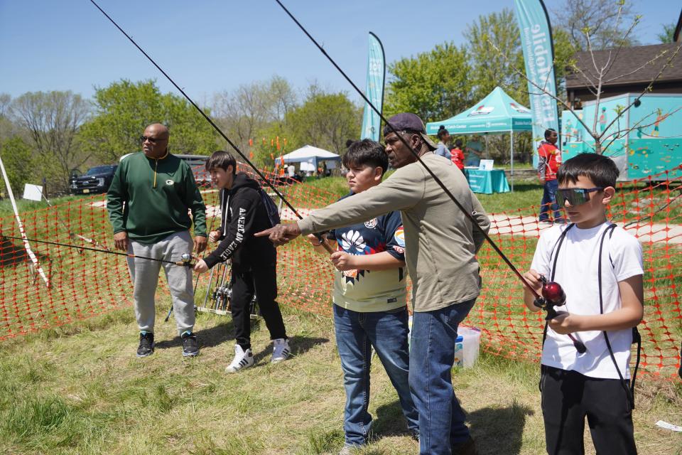 Howard Joplin of Milwaukee, far left, and  Cornelius Whiteside of Milwaukee give casting instructions to students at the Midwest Outdoor Heritage Education Expo. The men are members of the Inner City Sportsmen Club of Milwaukee. The event was held May 10 at Havenwoods State Forest in Milwaukee.
