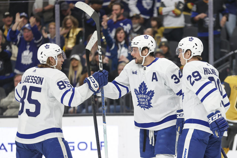 Toronto Maple Leafs defenseman William Lagesson (85) and right wing Pontus Holmberg (29) celebrate center Auston Matthews' goal against the Vegas Golden Knights during the third period of an NHL hockey game Thursday, Feb. 22, 2024, in Las Vegas. (AP Photo/Ian Maule)