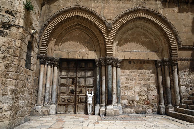 A man prays in front of the closed doors of the Church of the Holy Sepulchre on Palm Sunday, during Holy Week amid the coronavirus disease (COVID-19) outbreak, in Jerusalem's Old City