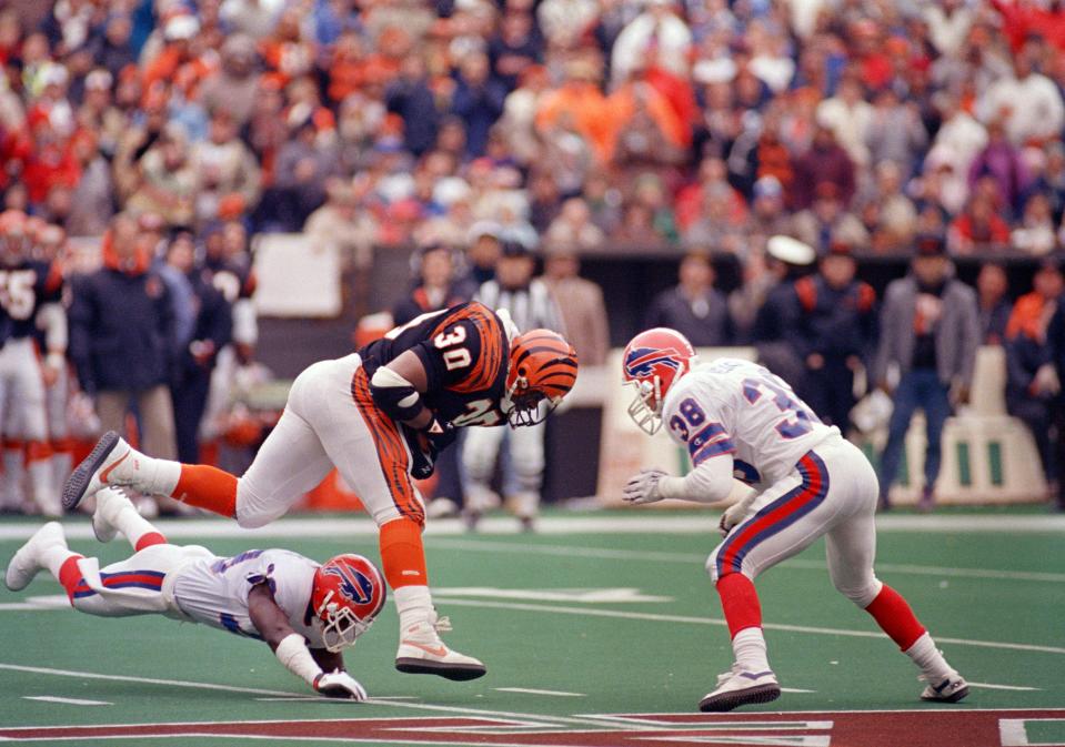 Cincinnati Bengals Ickey Woods (30) leaps past falling Buffalo Bills defender Derrick Burroughs on his way for open field in the second quarter of the AFC Championship game in Cincinnati, Jan. 8, 1989.