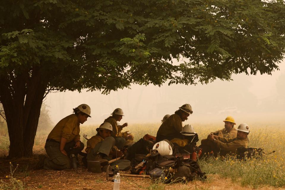 Firefighters wait under a tree as they battle the McKinney Fire (REUTERS)