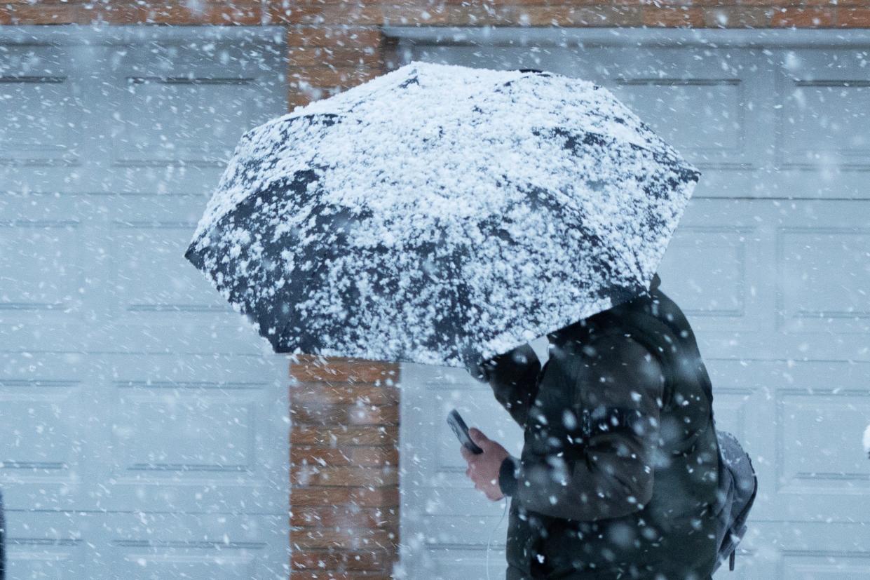 A man shields himself from the snow as it falls in Palisades Park, NJ on Tuesday Feb. 13, 2024.