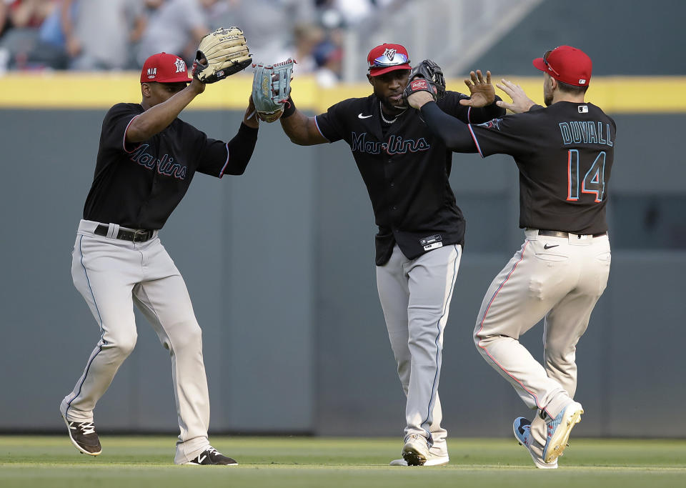 Miami Marlins' Adam Duvall (14) celebrates with Starling Marte, center, at the end of the team's baseball game against the Atlanta Braves on Saturday, July 3, 2021, in Atlanta. (AP Photo/Ben Margot)