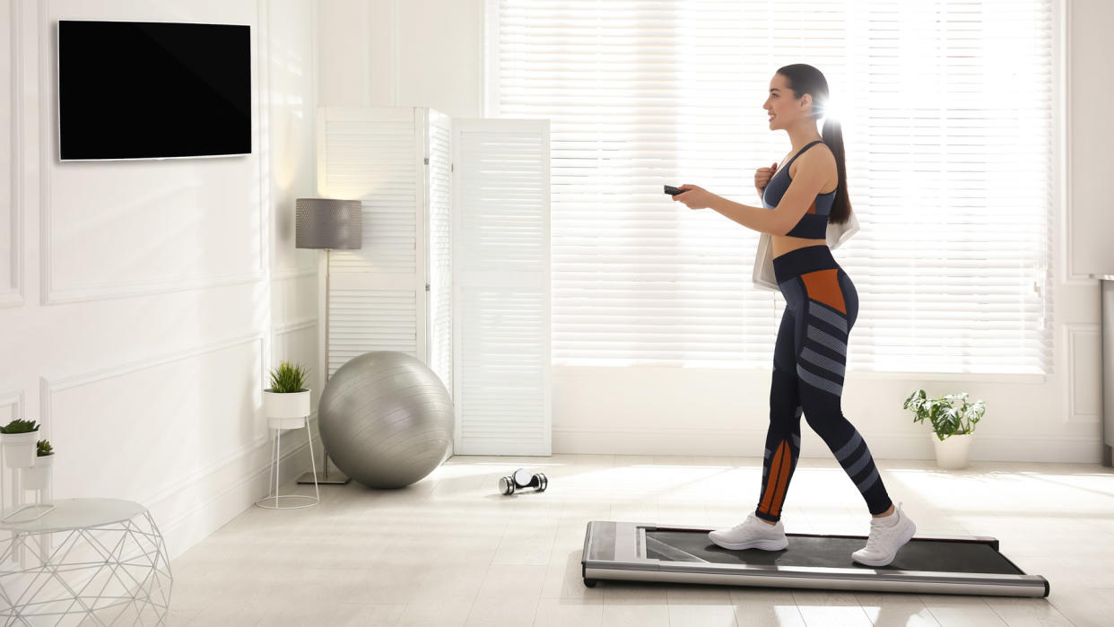  Woman using a walkingpad in front of TV. 