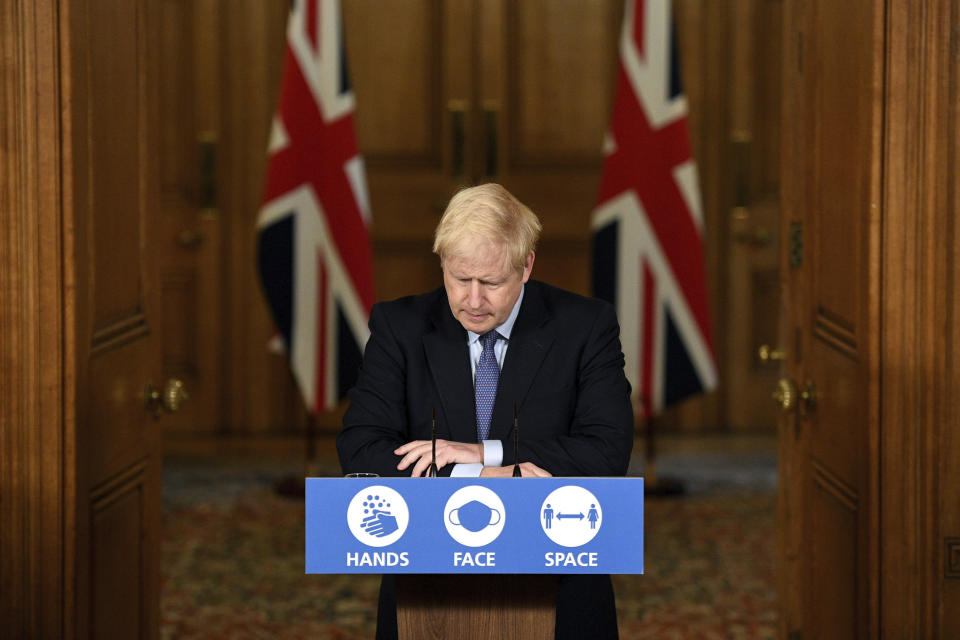 Britain's Prime Minister Boris Johnson listens, during a coronavirus media briefing in Downing Street, London, Tuesday, Oct. 20, 2020. British Prime Minister Boris Johnson says he is imposing the highest level of coronavirus restrictions on the Greater Manchester region, after days-long negotiations between his government and local leaders who reject the measures broke down with no deal reached. (Leon Neal/Pool Photo via AP)