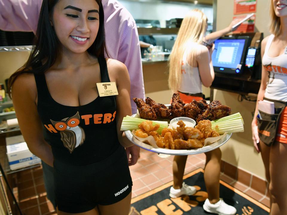  Hooters waitress Liberty Phan carries out a Buffalo Platter of wings Friday afternoon and the new restaurant on Call Field Road. The eatery opened Monday and Friday was their first day for lunch service.