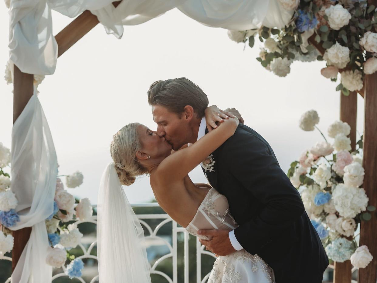 A bride and groom kiss during their wedding ceremony.