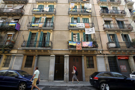 Banners against touristic apartments hang from balconies as people walk past them at Barceloneta neighborhood in Barcelona, Spain, August 18, 2015. REUTERS/Albert Gea/File Photo