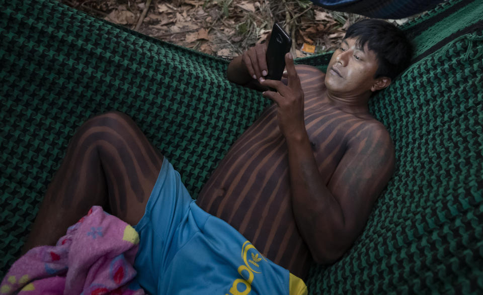 FILE - In this Aug. 19, 2020 file photo, a Kayapo Indigenous man checks his cellphone while resting in a hammock near Novo Progresso, Para state, Brazil. Although Indigenous communities have gained greater access to technology and the internet in recent years, information often arrives in a very distorted way. That means vaccine skepticism has gained even more traction in a place where it is sorely needed amid a crushing wave of infections and the spread of a worrisome variant of COVID-19. (AP Photo/Andre Penner, File)