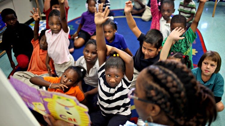 Students raise their hands anxiously to call out a word during a reading exercise in Tameka Warren's kindergarten class at K.E. Cunningham Canal Point Elementary