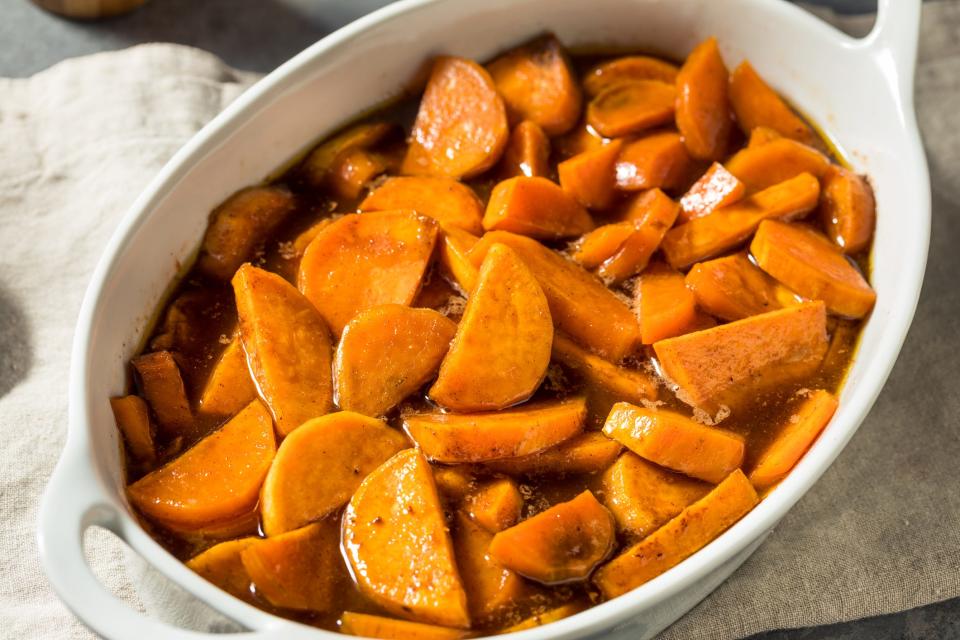 A casserole dish of baked sweet potatoes with brown sugar.