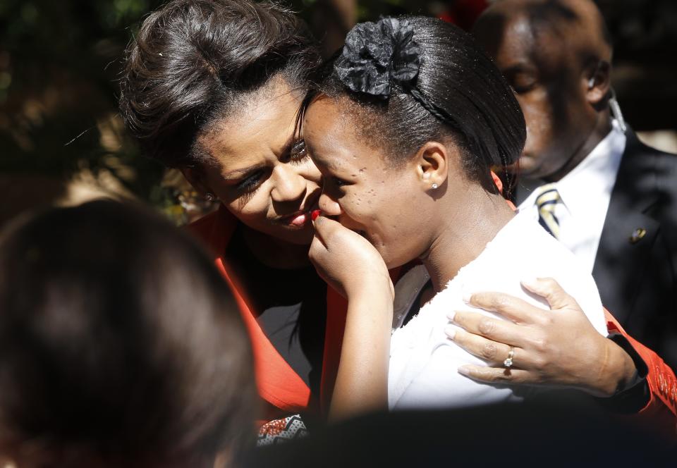 FILE - In this June 24, 2011, file photo, U.S. first lady Michelle Obama comforts a woman overcome with emotion as she greeted her at a multi-generational women leaders luncheon at the Sanitas Tea Garden in Gaborone, Botswana. When Melania Trump flies to Africa on her first extended international journey without the president, she’ll be following in the footsteps of her recent predecessors. (AP Photo/Charles Dharapak, File)