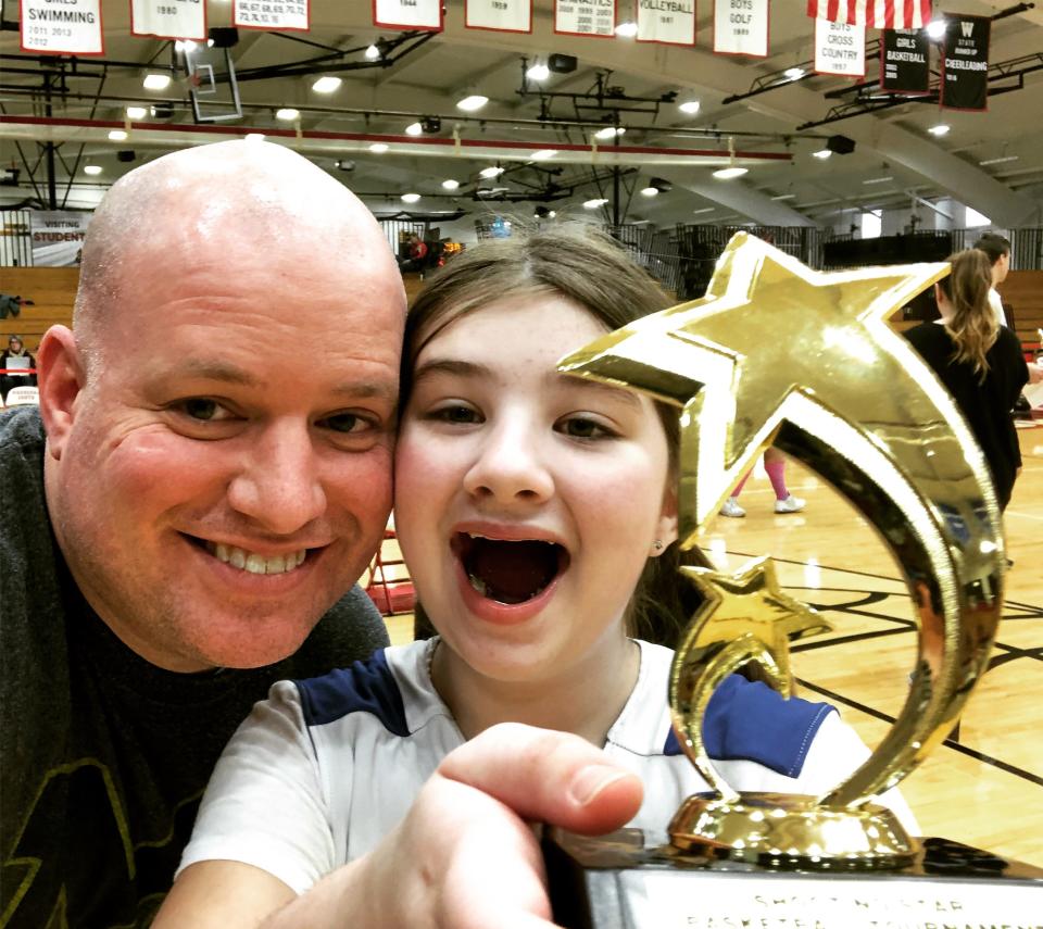 Keira Thompson, who wrote a children's book about her love of basketball, shows off a basketball trophy with her dad, John Thompson.