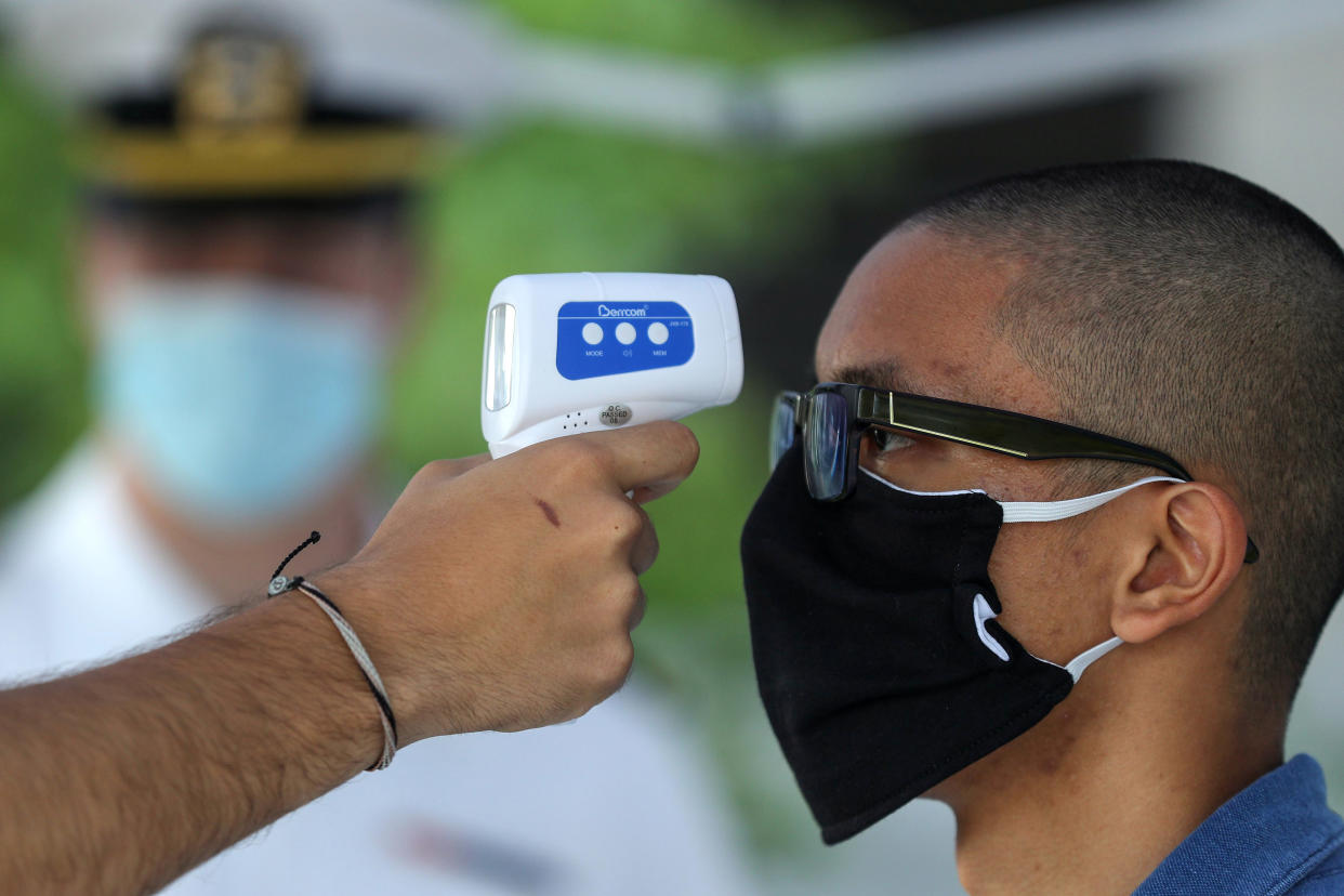 A new study suggests temperature checks may not be effective in catching COVID-19. Here, a Naval Academy plebe has their temperature taken before entering Alumni Hall on Induction Day in June. (Photo by Patrick Smith/Getty Images)