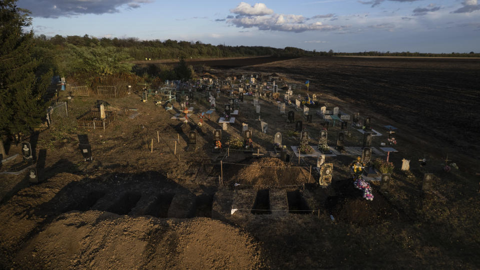 Aerial view shows newly dug empty graves at Hroza cemetery for people who were killed last Thursday by a Russian rocket attack on a village store and cafe, at the cemetery in Hroza, near Kharkiv, Ukraine, Sunday, Oct. 8, 2023. (AP Photo/Alex Babenko)