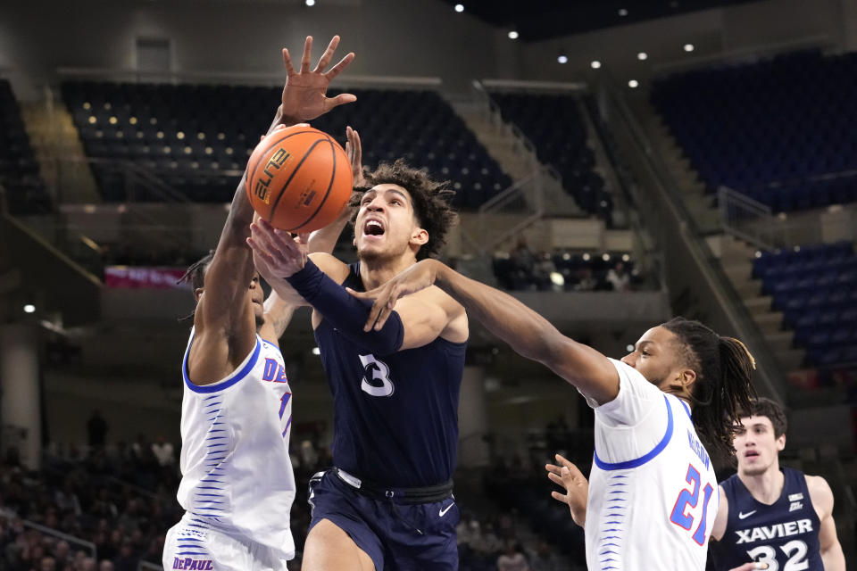 Xavier's Colby Jones (3) is fouled by DePaul's Da'Sean Nelson (21) as Jones drives to the basket between Nelson and Eral Penn during the first half of an NCAA college basketball game Wednesday, Jan. 18, 2023, in Chicago. (AP Photo/Charles Rex Arbogast)