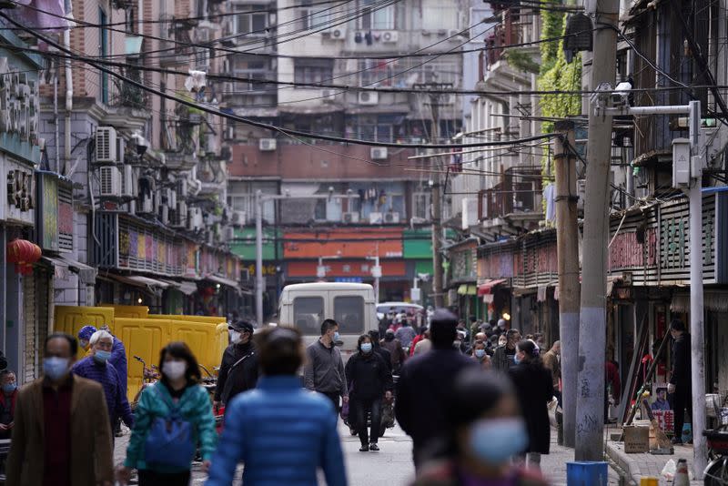 FILE PHOTO: People wearing face masks walk on a street market in Wuhan