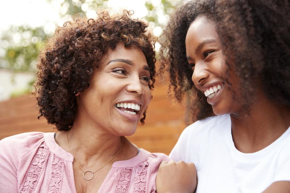 middle aged mom and teen daughter smiling at each other