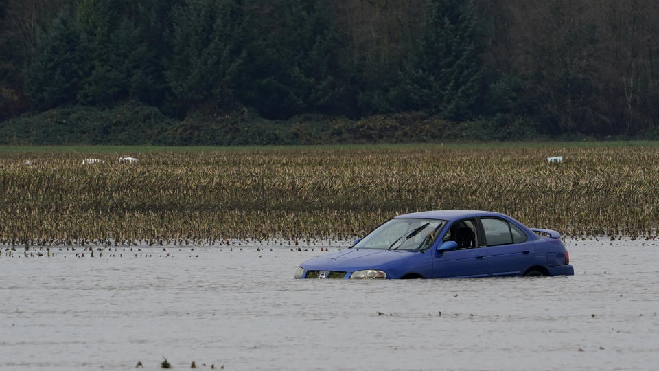 A car that was stranded earlier in the month remains under floodwaters in a field near Sumas, Wash., Monday, Nov. 29, 2021. People in Sumas, located near the Canadian border, were asked to evacuate voluntarily Saturday night, as communities in the area were still dealing with flooding from a storm earlier in the month. (AP Photo/Elaine Thompson)