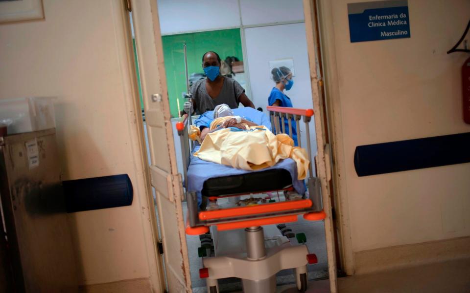 A health worker pushes a Covid-19 patient into a new ward in a hospital in Rio de Janeiro, Brazil -  MAURO PIMENTEL/AFP via Getty Images