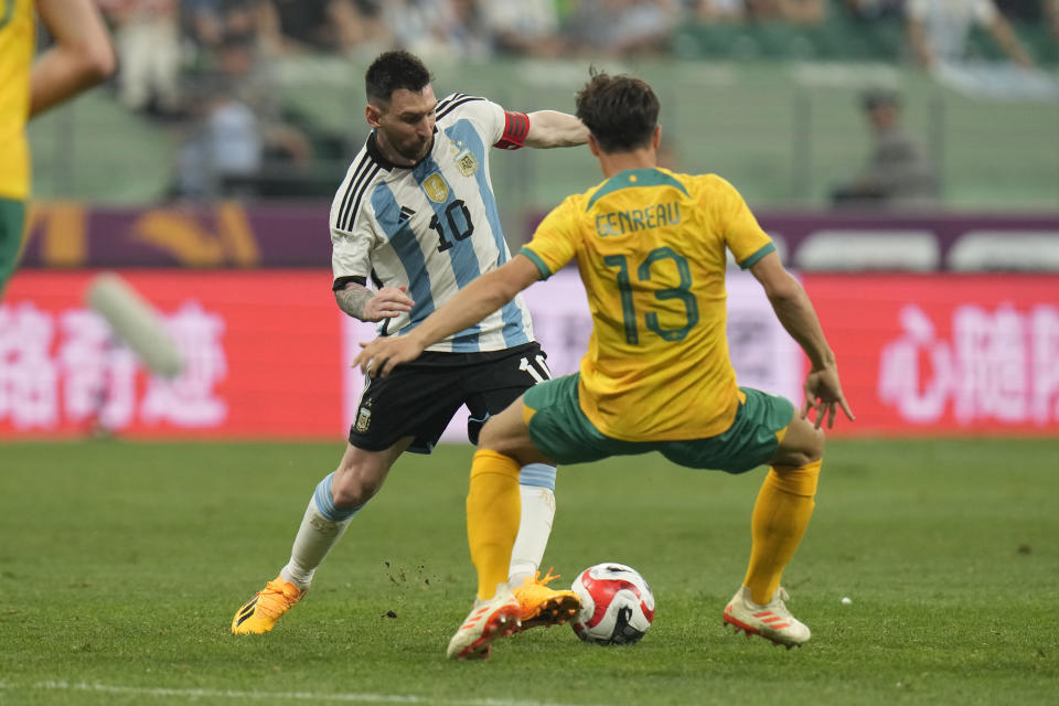 Argentina's Lionel Messi, left, battles for the ball against Australia's Dennis Genreau during their friendly soccer match at the Workers' Stadium in Beijing, China, Thursday, June 15, 2023. (AP Photo/Andy Wong)