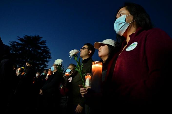 People hold candles as they pay tribute to the victims of the mass shooting at a candlelight vigil in front of City Hall in Monterey Park on Tuesday.