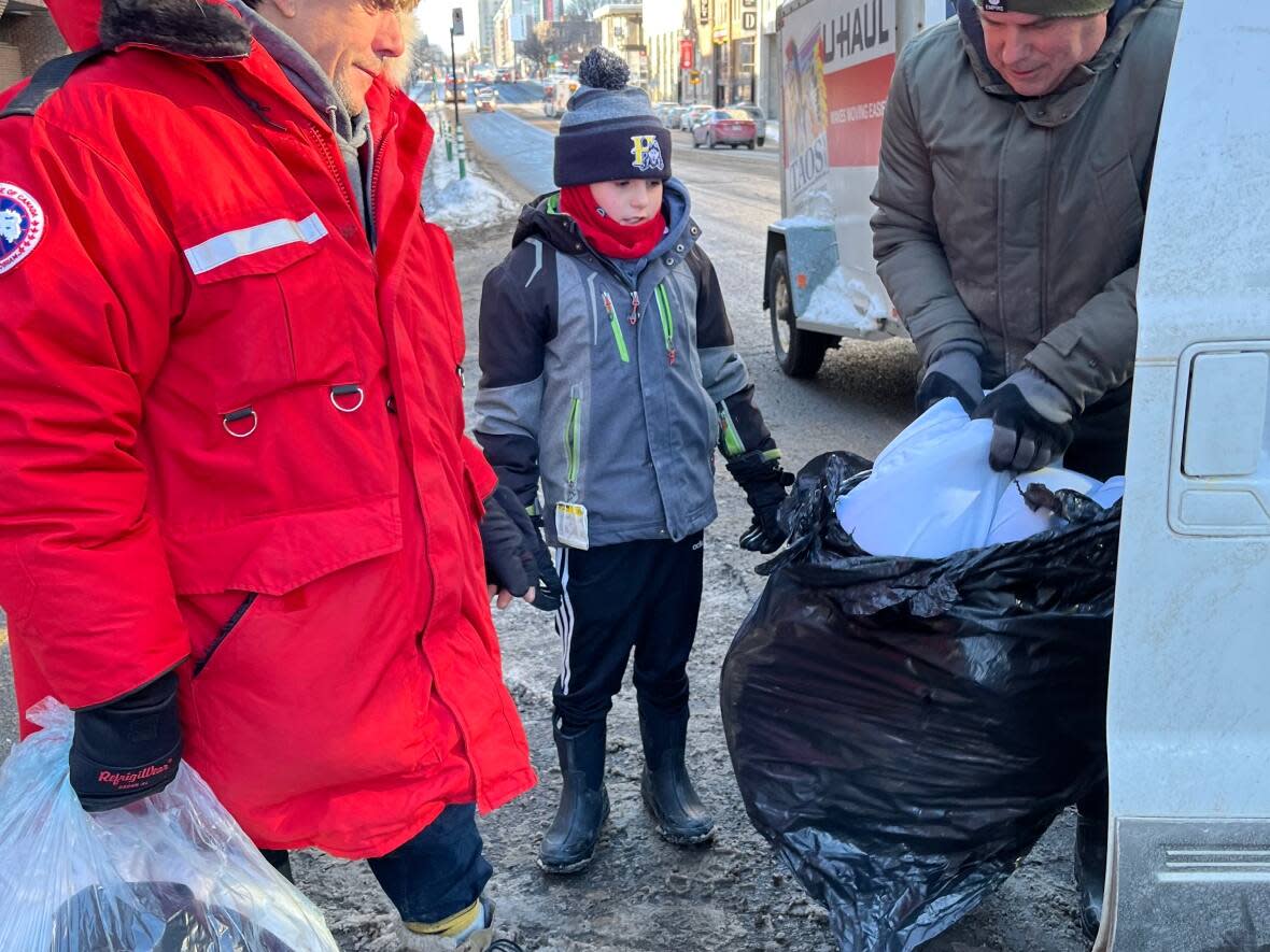 Logan Laguë (middle) and Marc-André Laguë (right) after handing out a jacket and hat in Montreal last weekend. (Submitted by Cynthia Royea - image credit)