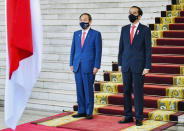 In this photo released by Indonesian Presidential Palace, Japanese Prime Minister Yoshihide Suga, left, and Indonesian President Joko Widodo listen to the national anthems during their meeting at the Presidential Palace in Bogor West Java, Indonesia, Tuesday, Oct 20, 2020. (Laily Rachev/Indonesian Presidential Palace via AP)