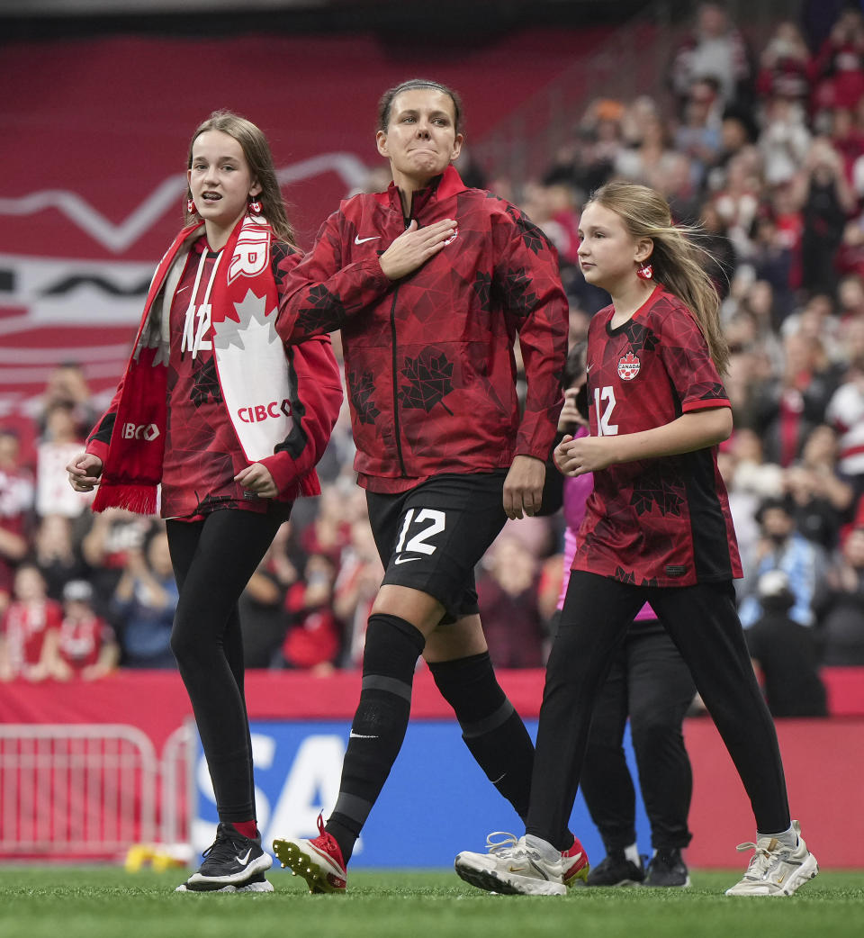 Canada's Christine Sinclair walks onto the field with her nieces Kaitlyn and Kenzie to be honored before the team's international friendly soccer match against Australia on Tuesday, Dec. 5, 2023, in Vancouver, British Columbia. Sinclair, 40, was making her 331st and final appearance for Canada. (Darryl Dyck/The Canadian Press via AP)