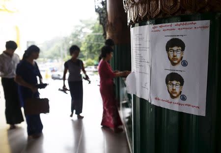 People line up as they leave their slippers near a wanted poster for the main suspect of a deadly bomb blast in Bangkok, Thailand, put up by local authorities at Shwedagon pagoda in Yangon, Myanmar August 25, 2015. Poster reads: "Suspect wanted in Bangkok bomb blast. Please contact this number if found." RETUERS/Soe Zeya Tun