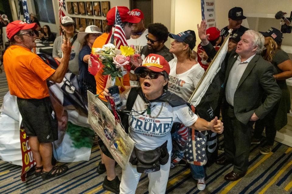 Several people in Trump hats and shirts protesting indoors.