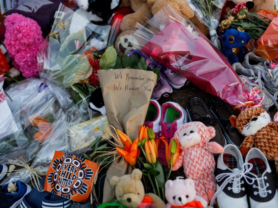 Un mensaje está garabateado en flores en un memorial improvisado en la antigua escuela residencial india de Kamloops para honrar a los 215 niños cuyos restos han sido descubiertos enterrados cerca de las instalaciones. (AFP via Getty Images)