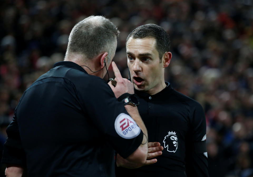 Referee Jonathan Moss speaks with the his assistant Eddie Smart before awarding a penalty to Tottenham