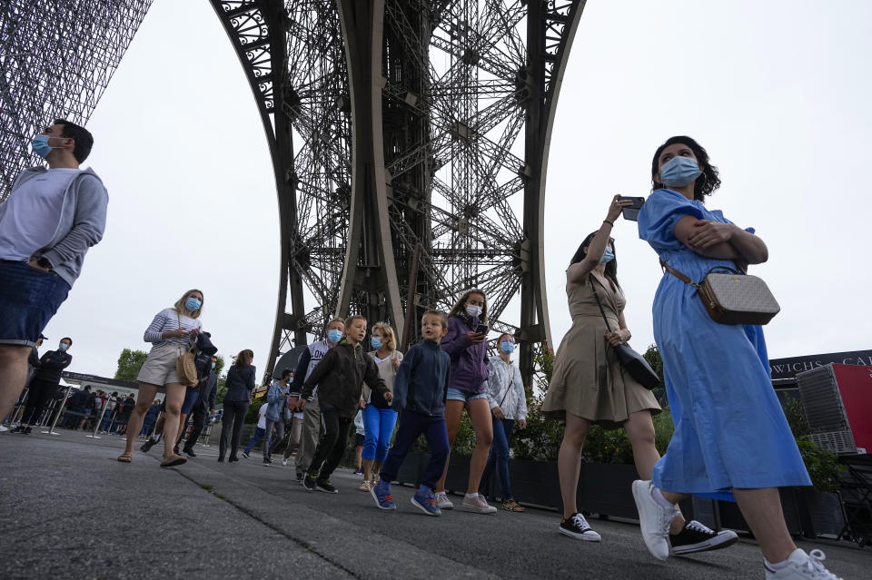 Visitors arrive at the Eiffel Tower in Paris, Friday, July 16, 2021. The Eiffel Tower is reopening Friday for the first time in nine months, just as France faces new virus rules aimed at taming the fast-spreading delta variant. The "Iron Lady" was ordered shut in October as France battled its second surge of the virus. (AP Photo/Michel Euler)