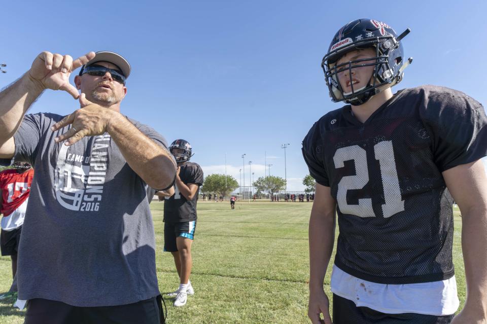 Desert Ridge High School football head coach Jeremy Hathcock coaches his players and his son, Koby, a junior strong safety during their football practice in Mesa, AZ.