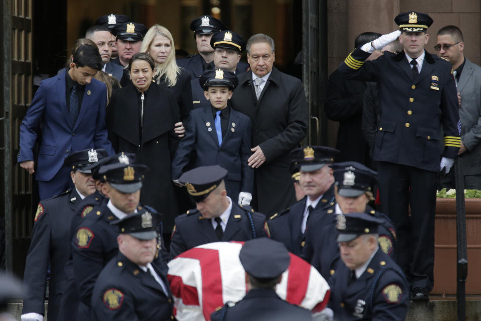 The family of Jersey City Police Detective Joseph Seals, including his wife Laura Seals, center left, watch as his casket is carried out of the church in Jersey City, N.J., Tuesday, Dec. 17, 2019. The 40-year-old married father of five was killed in a confrontation a week ago with two attackers who then drove to a kosher market and killed three people inside before dying in a lengthy shootout with police. (AP Photo/Seth Wenig)