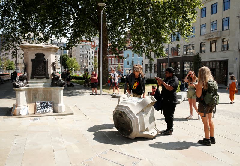 People observe the base of the statue of Edward Colston