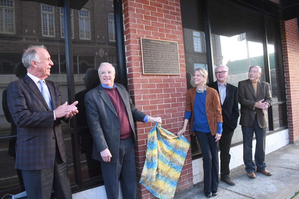 The partners of 301 Jackson Place, Patrick Moore (far left), Lindsey Torbett, Moore's wife Randall Moore, Thomas McBride and R.J. Dunn unveil a historical plaque for the building that McBride said was the oldest known commerical structure in Alexandria. The plaque is located on the side of the building facing Jackson Street.