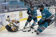 Vegas Golden Knights center Chandler Stephenson, left, reaches behind for the puck next to San Jose Sharks defensemen Mario Ferraro (38) and Brent Burns (88) during the second period of an NHL hockey game in San Jose, Calif., Wednesday, May 12, 2021. (AP Photo/Jeff Chiu)