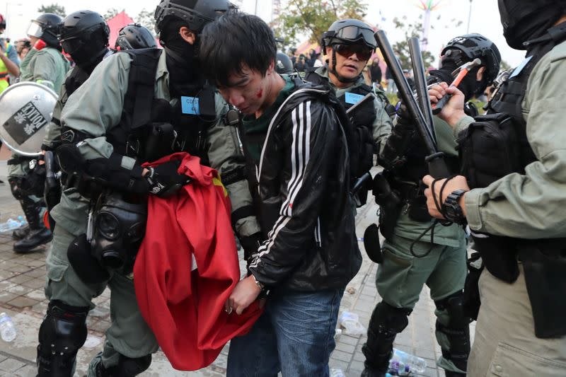 Police arrest a Hong Kong protester after a Chinese flag was removed from a flag pole at a rally in support of Xinjiang Uighurs' human rights in Hong Kong