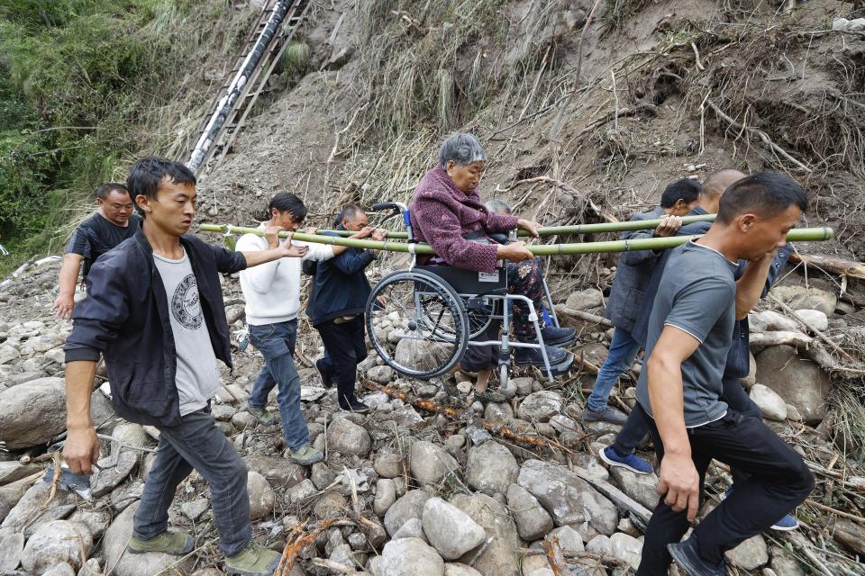 In this photo released by Xinhua News Agency, people carry out an injured person evacuated in the aftermath of an earthquake from Mozigou village near Moxi Town of Luding County, southwest China's Sichuan Province, Sept. 8, 2022. Heavy rains are complicating earthquake recovery efforts in southwestern China, where the death toll from Monday's disaster has risen. (Shen Bohan/Xinhua via AP)