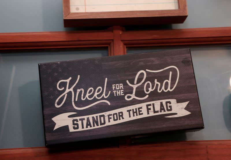 A sign reading "Kneel for the Lord, Stand for the Flag" hangs in the home of Michigan Republican Bree Moeggenberg in Mount Pleasant