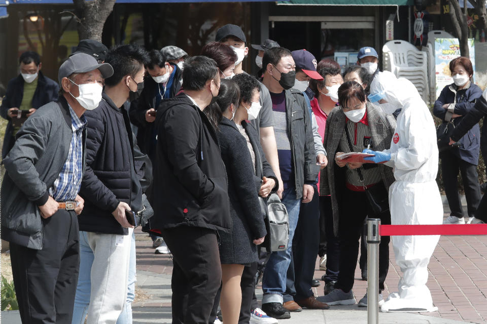 A health official checks names of migrant workers as they wait for coronavirus testing at a makeshift clinic in Seoul, South Korea, Friday, March 19, 2021. Britain's ambassador to South Korea on Thursday criticized South Korean health authorities for mandating coronavirus tests on all foreign workers in capital Seoul and nearby Gyeonggi Province in a mass testing campaign that has triggered complaints about racial discrimination. (AP Photo/Ahn Young-joon)