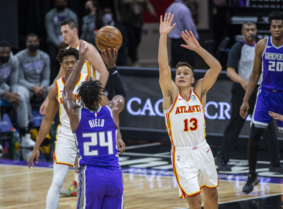 Sacramento Kings guard Buddy Hield (24) hits a 3-point basket as he's defended by a former teammate, Atlanta Hawks guard Bogdan Bogdanovic (13), during the first quarter of an NBA basketball game in Sacramento, Calif., Wednesday, March 24, 2021. (AP Photo/Hector Amezcua)