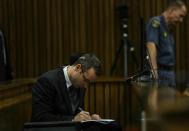 Oscar Pistorius makes notes as he sits in the dock and listens to cross questioning about the events surrounding the shooting death of his girlfriend Reeva Steenkamp, in court during his trial in Pretoria, South Africa, Tuesday, March 11, 2014. Pistorius is charged with the shooting death of Steenkamp, on Valentines Day in 2013. (AP Photo/Kevin Sutherland, Pool)