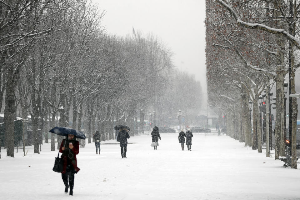 People stroll down on the Champs Elysees avenue during snowfall in Paris, Tuesday Jan.22, 2019. (AP Photo/Thibault Camus)